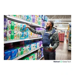 Black man wearing baby carrier and holding phone while reaching for diapers on supermarket shelf