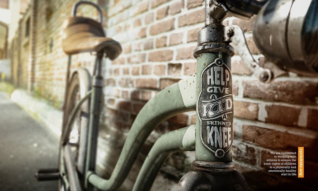Close-up of a vintage-style bicycle with a weathered frame, leather seat, and brick wall backdrop, creating a nostalgic, artistic composition.