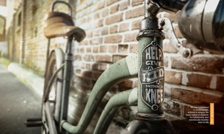 Close-up of a vintage-style bicycle with a weathered frame, leather seat, and brick wall backdrop, creating a nostalgic, artistic composition.