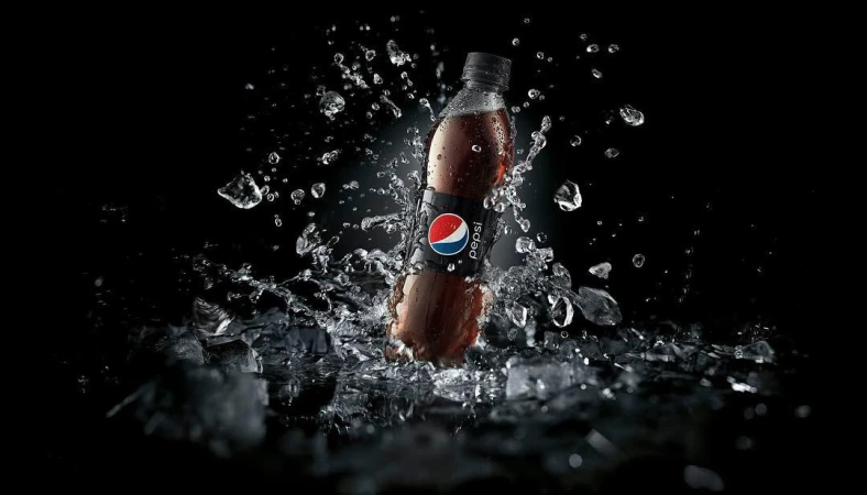 A bottle of Pepsi with water droplets and ice crystals around it is placed against a stark black backdrop, product photography.