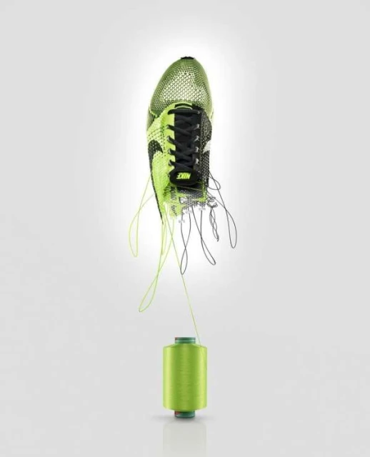Nike running shoe floats above a lime green spool of thread against a gradient white background in a studio product shot.