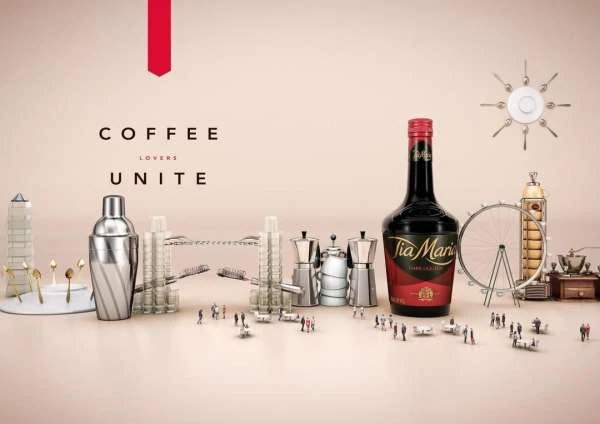 Tia Maria liqueur bottle with coffee accessories: shakers, grinders, miniature buildings and people in a product photography still life.