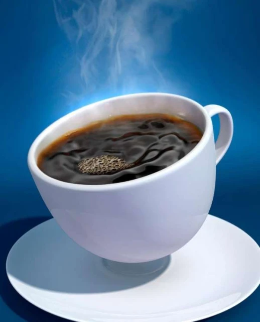 Steaming hot dark roast coffee fills a white ceramic mug and saucer against a solid graduated blue background in a studio setting.