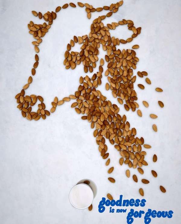 Almond cow art with white bowl and blue script, a modern food and beverage still life against a textured white background.