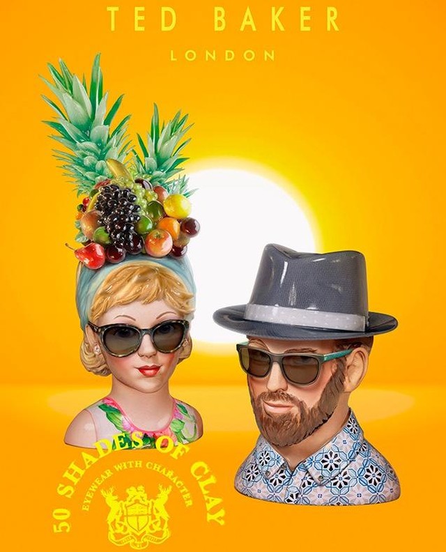 Two mannequin heads wearing sunglasses, one adorned with fruit and a headscarf, the other with a hat, against a bright orange background.