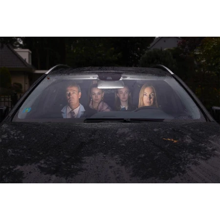 A family of four is visible inside a dark-colored SUV. The father is driving, and three young women are sitting in the backseats of the vehicle.
