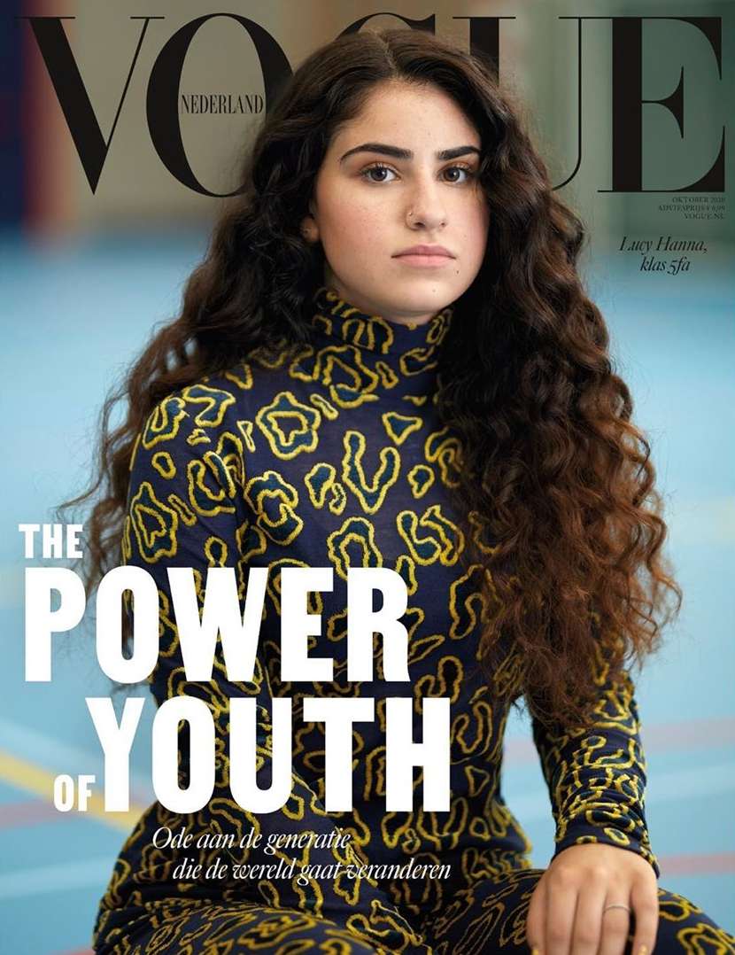 Vogue Nederland cover featuring a young woman with long, wavy dark hair, wearing a printed turtleneck top and looking directly at the camera.