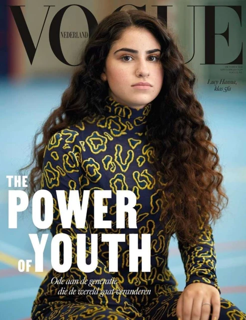 Vogue Nederland cover featuring a young woman with long, wavy dark hair, wearing a printed turtleneck top and looking directly at the camera.
