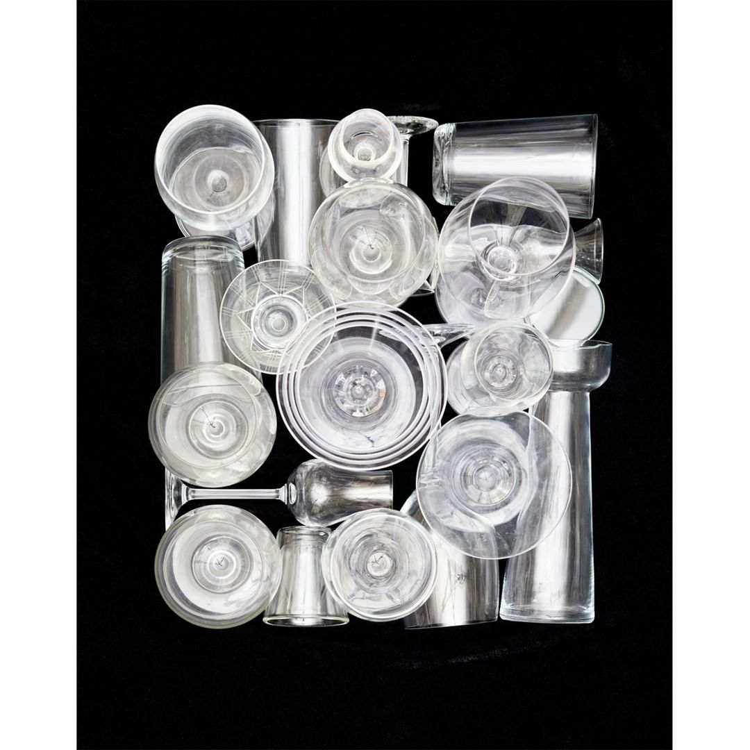 Arrangement of various clear glass drinkware on a black backdrop, creating a minimalist and modern composition with transparent textures.
