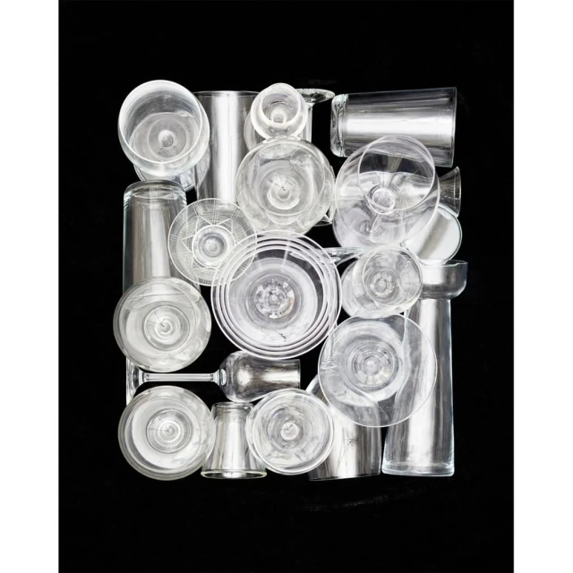 Arrangement of various clear glass drinkware on a black backdrop, creating a minimalist and modern composition with transparent textures.