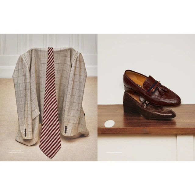 Beige plaid suit jacket and red striped tie next to a stack of brown leather loafers on a wooden shelf in front of a white wall.