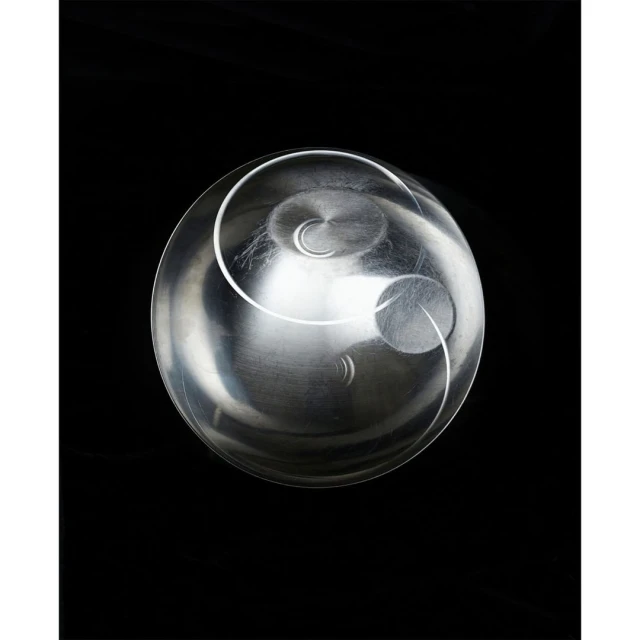 Abstract design featuring a clear glass bowl with a silver metallic interior and circular patterns against a solid black background.