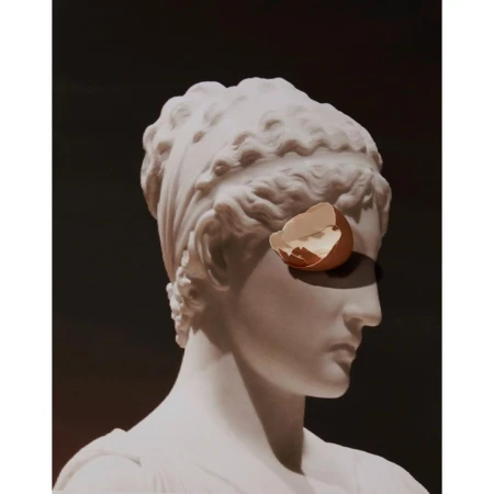 White statue bust of a woman with an eggshell on her eye, against a dark brown background, creative studio art, portrait orientation.