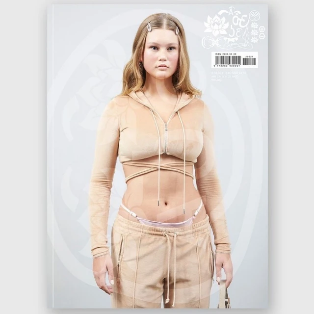 Magazine cover featuring a woman in a light brown sweatsuit with long hair, standing against a light background with abstract designs.