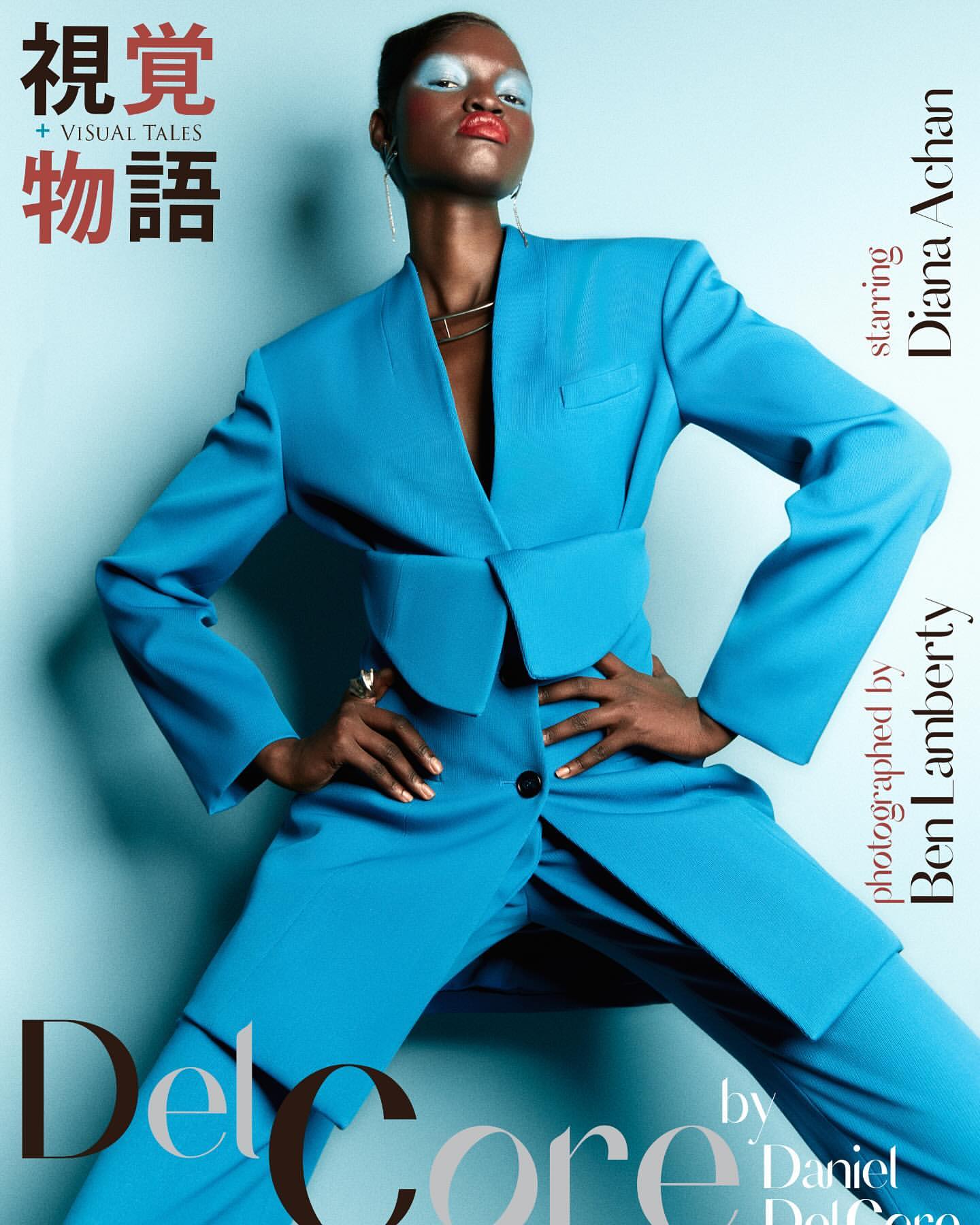 Fashion editorial portrait of Diana Achan in a bright blue suit with hands on hips, makeup with blue eyeshadow and red lipstick, angled full shot.