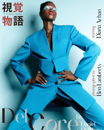 Fashion editorial portrait of Diana Achan in a bright blue suit with hands on hips, makeup with blue eyeshadow and red lipstick, angled full shot.