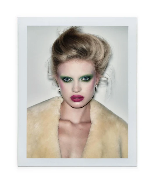 Portrait of a woman with elaborate makeup, including green eyeshadow and pink lipstick, posing in front of a neutral background.