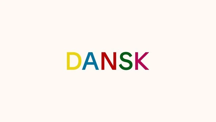 DANSK graphic design with block-letter logo in yellow, blue, red, green, and magenta on cream background in a studio setting.