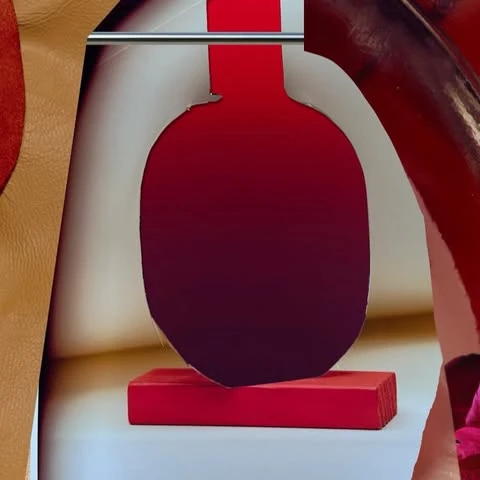 Abstract fashion photograph of an oval cutout in front of leather and a metal rod, using red and white colors, shot in a studio.