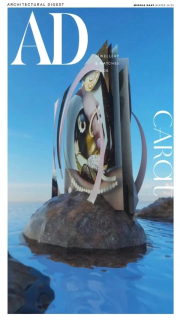Magazine cover features jewelry art installation on a rock in the water. The sky is blue in the background and includes the publication's name.