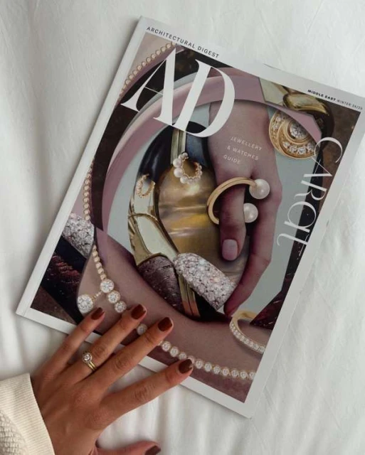 Magazine cover featuring jewellery on a hand, beside a woman's hand with rings, set against a white fabric background.