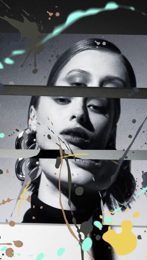 Portrait of a woman with heavy eye makeup wearing large hoop earrings, digitally altered with paint-like splashes of color.