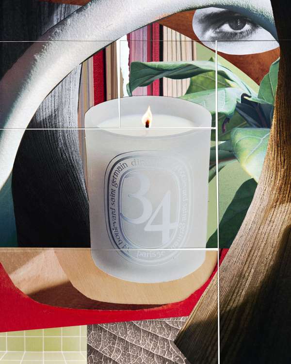Frosted candle on a surface with books and a drawing of an eye in the background, creating a still life product shot.