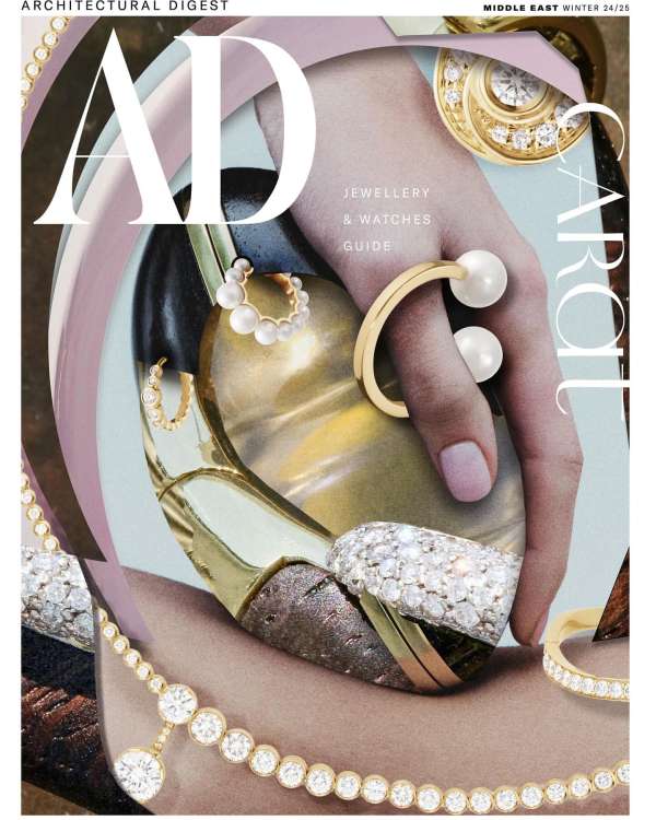 Magazine cover featuring an individual's hand adorned with luxurious jewelry, including rings, earrings, and a necklace with gems.