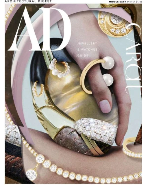 Magazine cover featuring an individual's hand adorned with luxurious jewelry, including rings, earrings, and a necklace with gems.