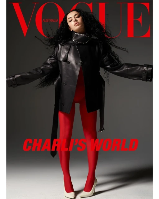 Vogue Australia cover featuring a woman with black curly hair wearing a black leather jacket, red tights, and white heels, set against gray backdrop.