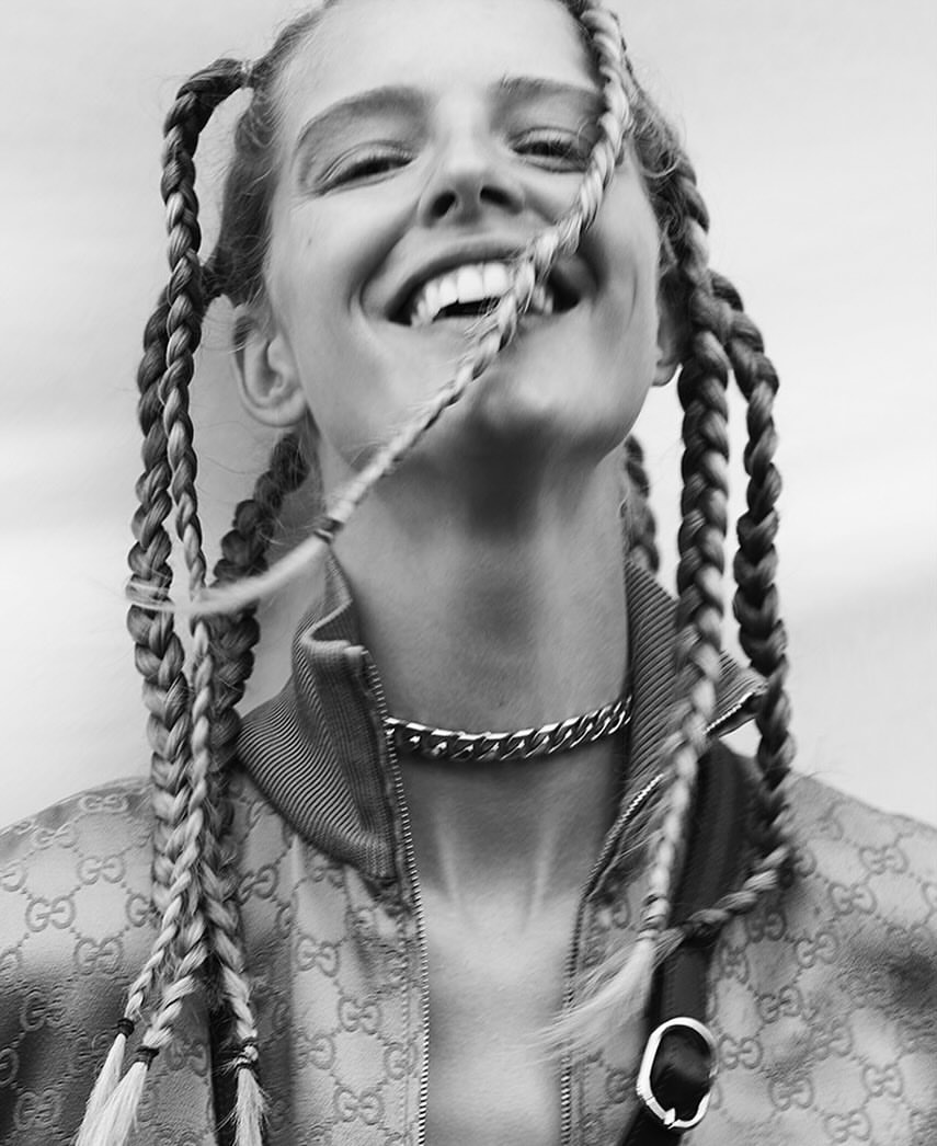 Smiling woman in Gucci jacket with braided hair. Close-up portrait in black and white, silver chain necklace, fashion.