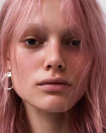 Close-up portrait of a woman with pink hair and hoop earrings captured by photographer Amy Troost.