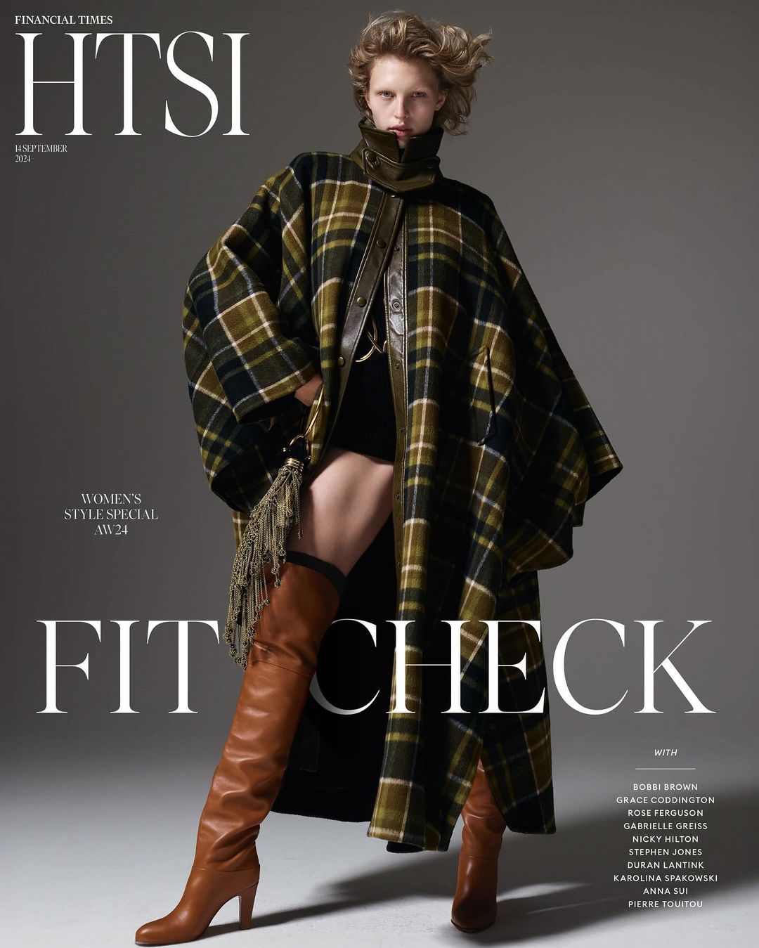 Fashion editorial featuring a woman in a plaid cape coat and thigh-high boots, Financial Times HTSI magazine cover, studio shot.