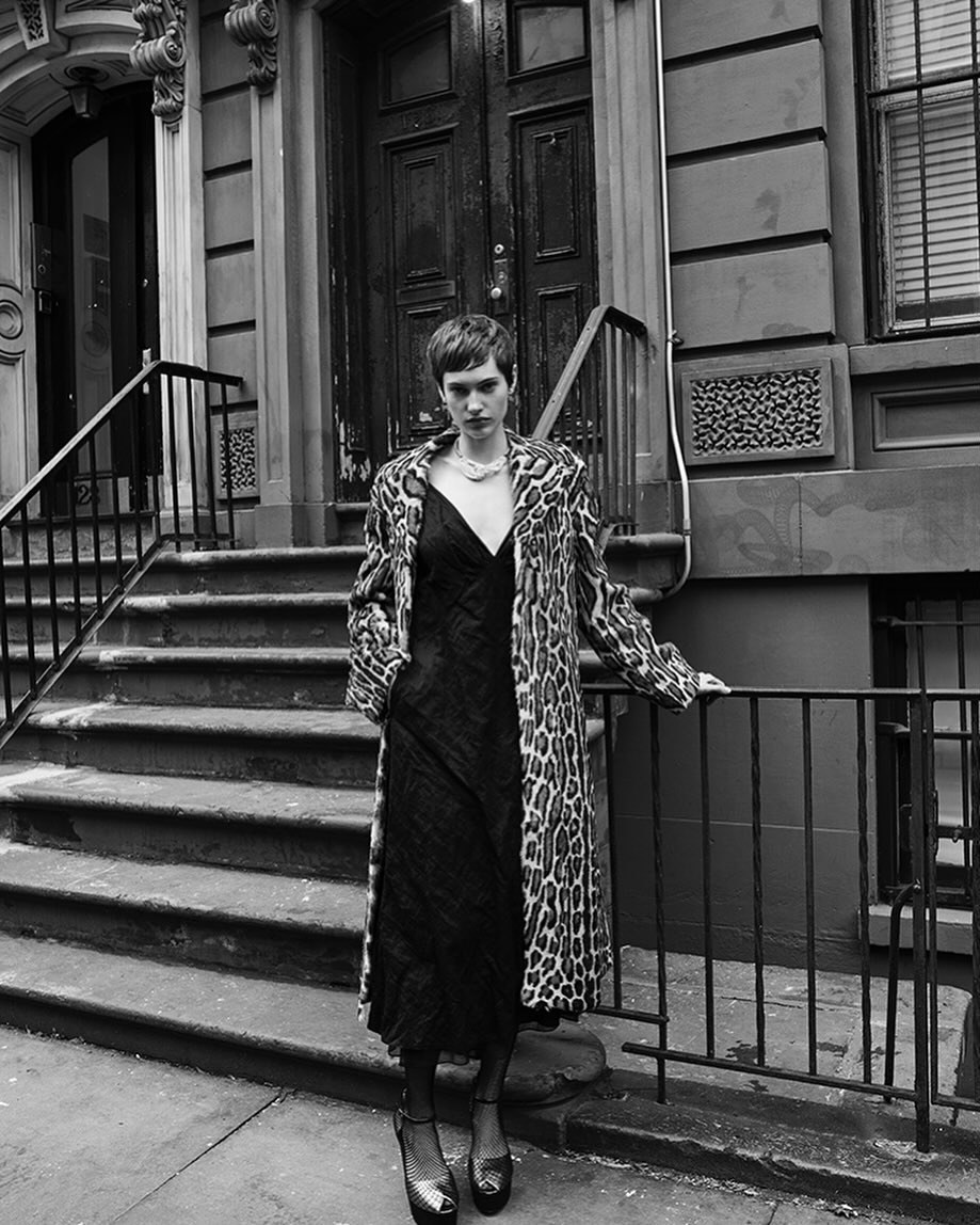 Model wearing a leopard print coat and dark slip dress standing on brownstone stoop by Amy Troost