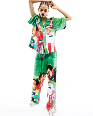 Model with braided hair in green printed short-sleeve shirt and matching trousers posing against a white background