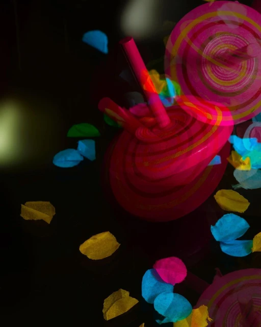 Close-up of two pink and yellow lollipops with colorful wrappers on a dark background creating a whimsical and vibrant visual.