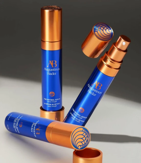 Augustinus Bader retinol serum bottles with blue and copper packaging on a neutral surface. Beauty and skincare product photography.