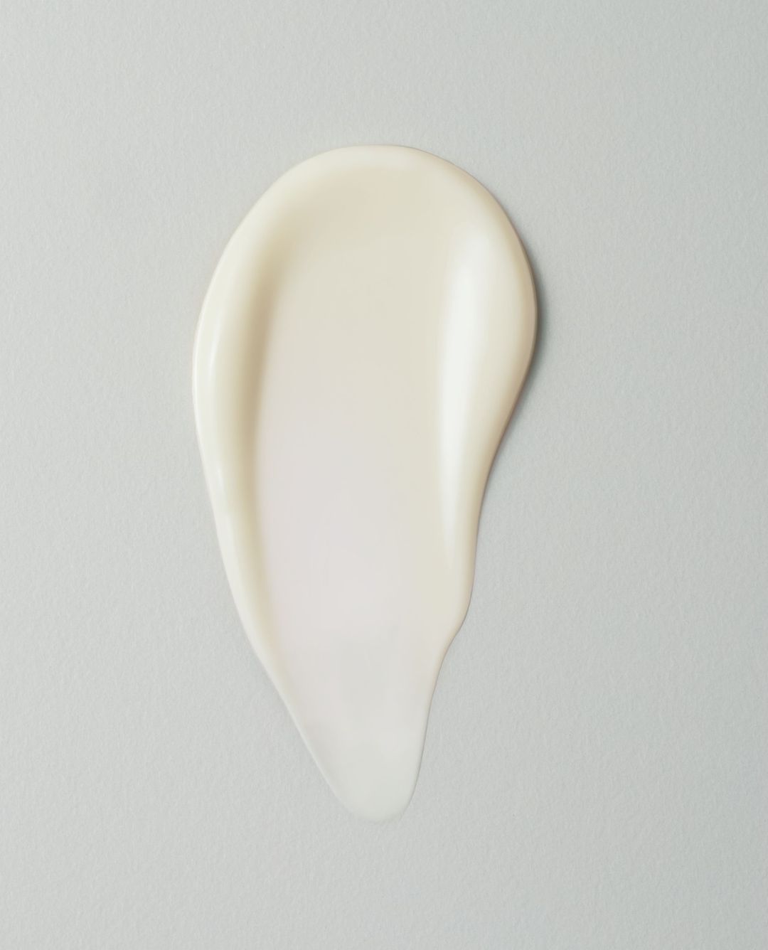 Close-up studio shot of white cream smear on a light gray backdrop, ideal for beauty or skincare product promotion.