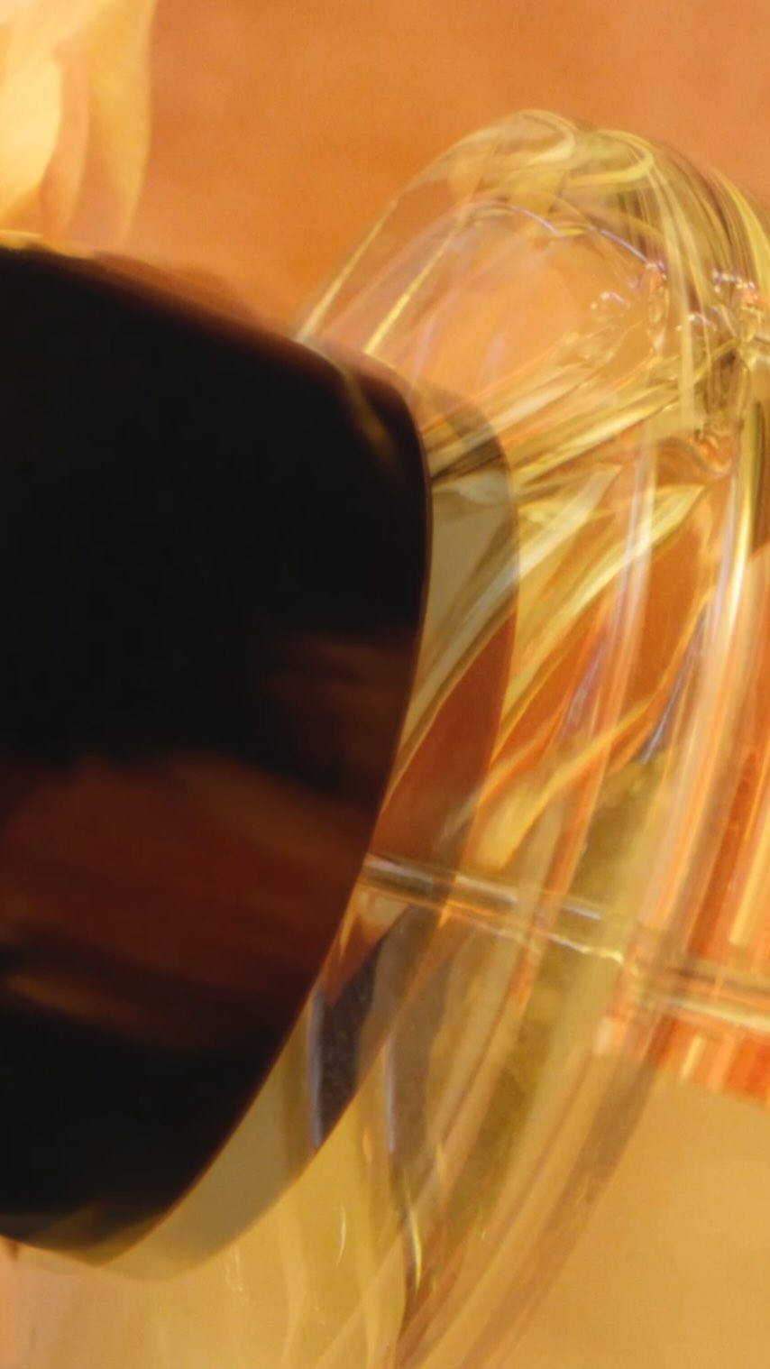 Abstract macro image featuring translucent yellow and orange glass-like material with a smooth surface against a diffused orange backdrop.