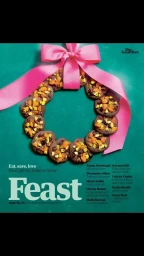 Chocolate biscuit wreath topped with fruit and nuts, tied with a bright pink ribbon on a teal background.