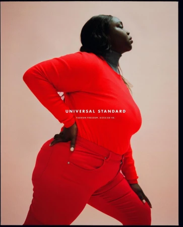 Portrait of an African-American woman wearing a red long-sleeved shirt and red pants in a studio setting, posing against a light peach background.