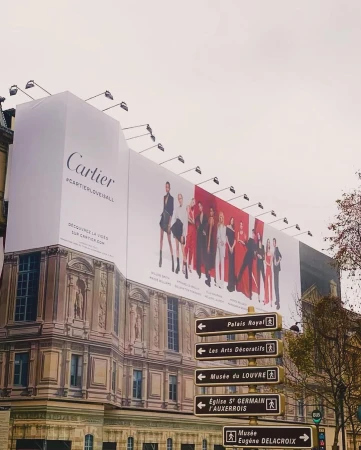 Outdoor billboard in Paris promotes Cartier with a group of fashion models dressed in black, red, and white formalwear.