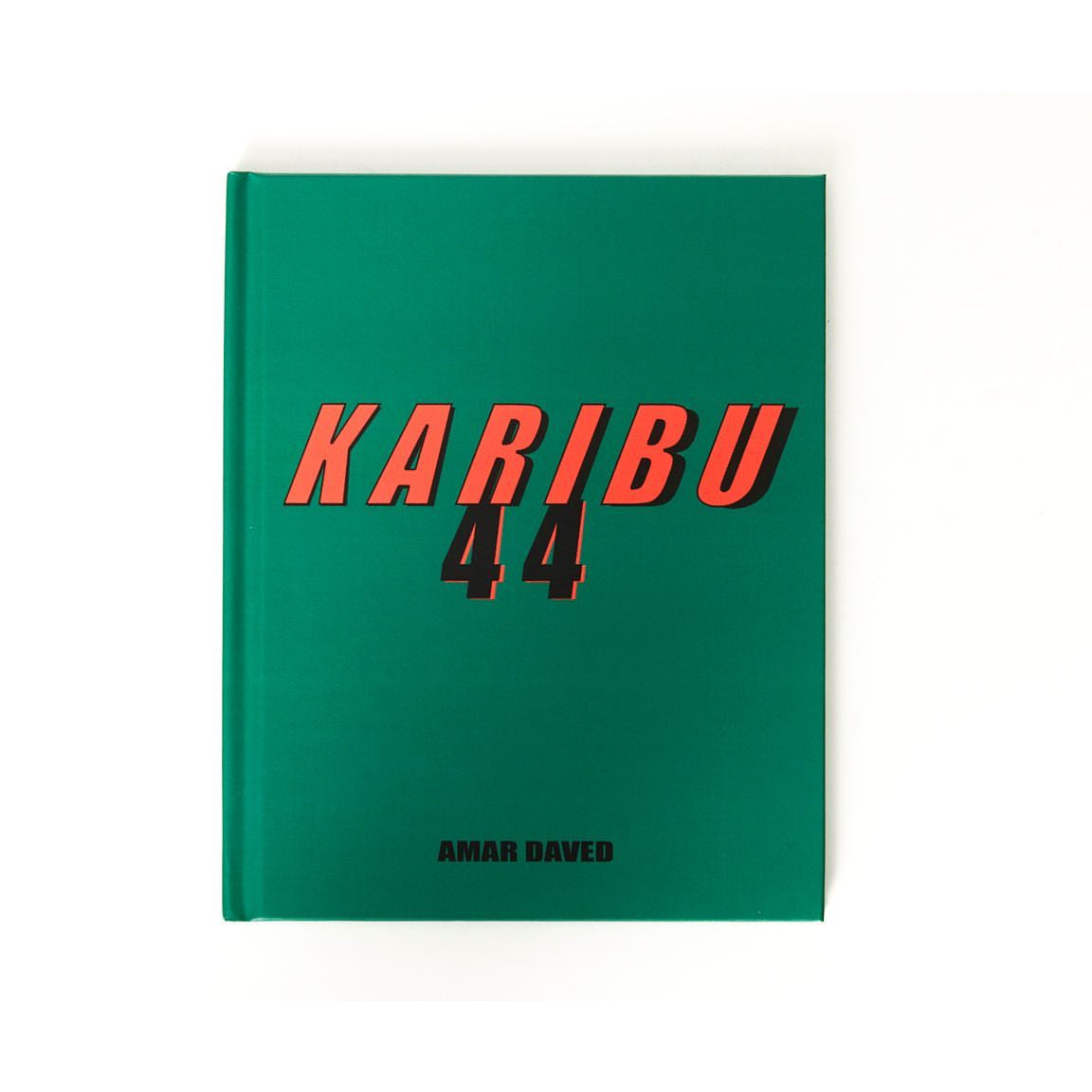 A studio shot of a hardback book with a green cover with the text “Karibu 44” in orange, against a plain white backdrop.