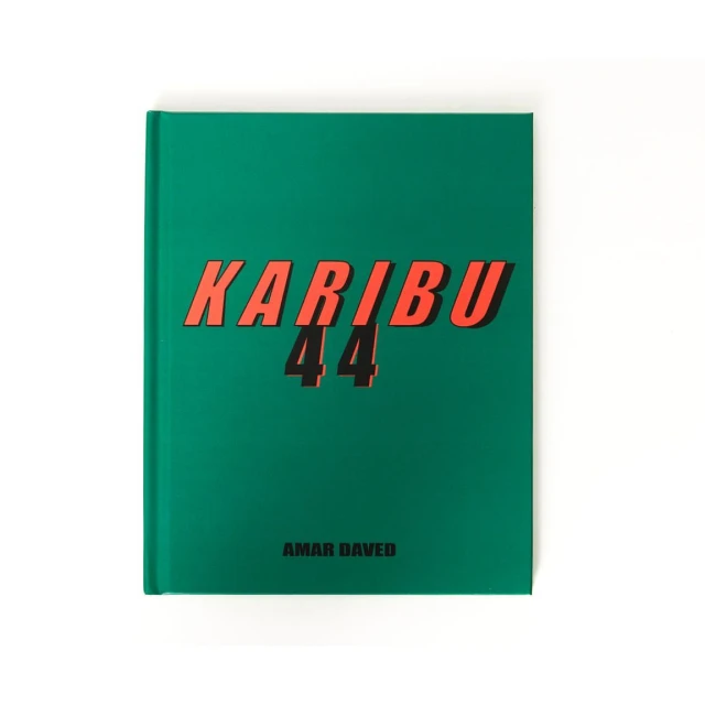 A studio shot of a hardback book with a green cover with the text “Karibu 44” in orange, against a plain white backdrop.