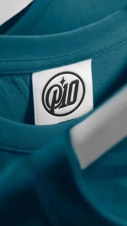 Close-up on a teal t-shirt featuring a brand label with the 'P10' logo in black, offering a detailed view of the garment.