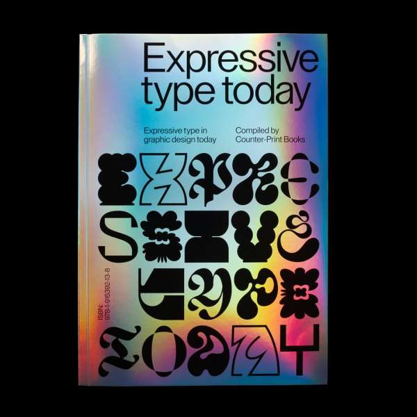 Close-up studio shot of a book titled 'Expressive Type Today' with bold, abstract typography on its iridescent, multicolored cover.