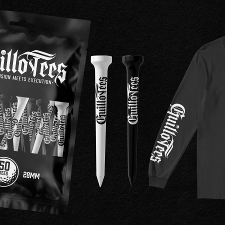 Close-up studio shot of black and white golf tees with Guillotees logo, displayed next to a matching logo-branded sleeve and packaging.