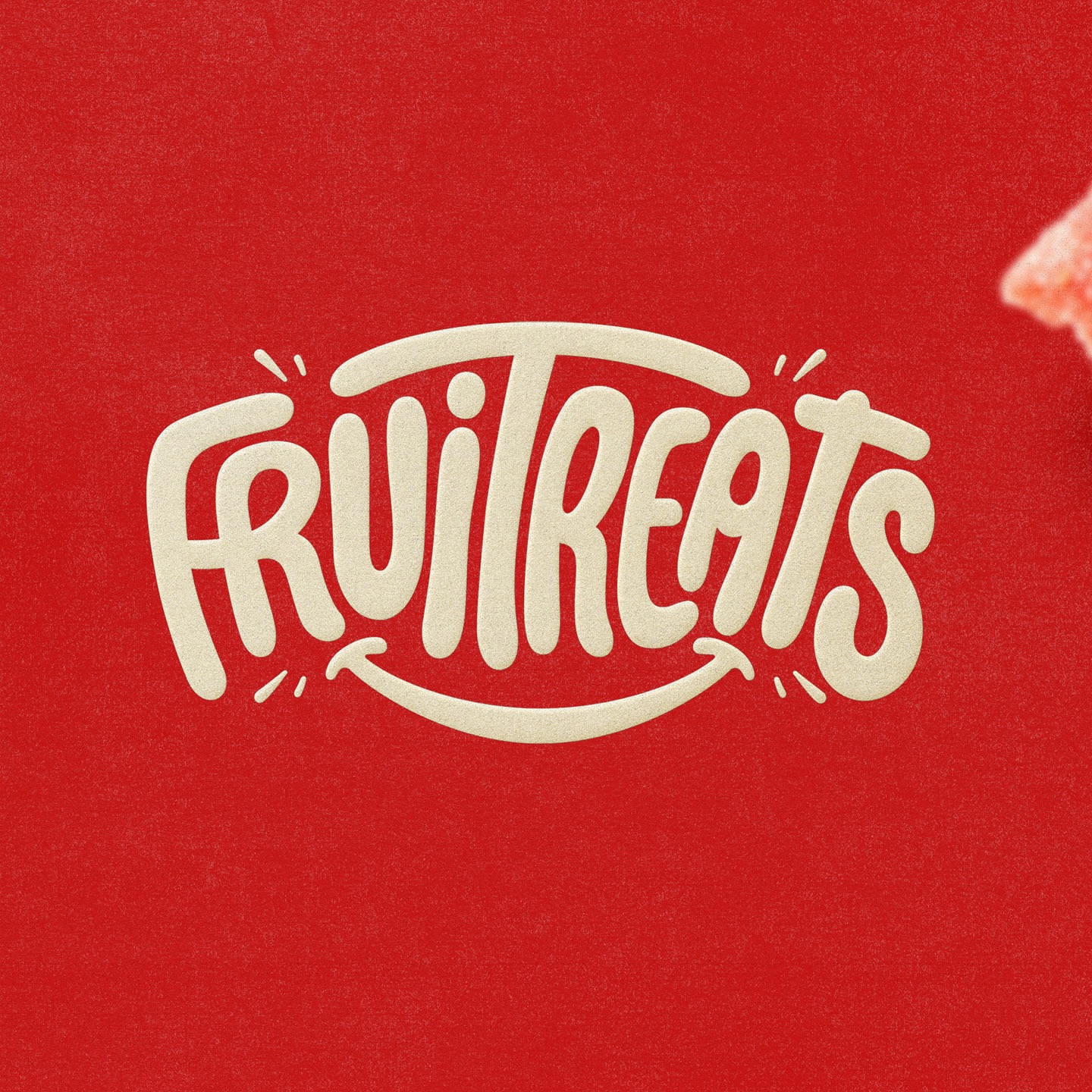 Close-up on the Fruitreats logo in white against a red background, with a small corner of an orange gummy visible.
