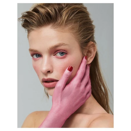 Close-up portrait of a woman with wet-look hair, pink eyeshadow, and a hand painted pink covering part of her face.