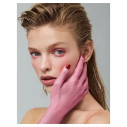 Close-up portrait of a woman with wet-look hair, pink eyeshadow, and a hand painted pink covering part of her face.